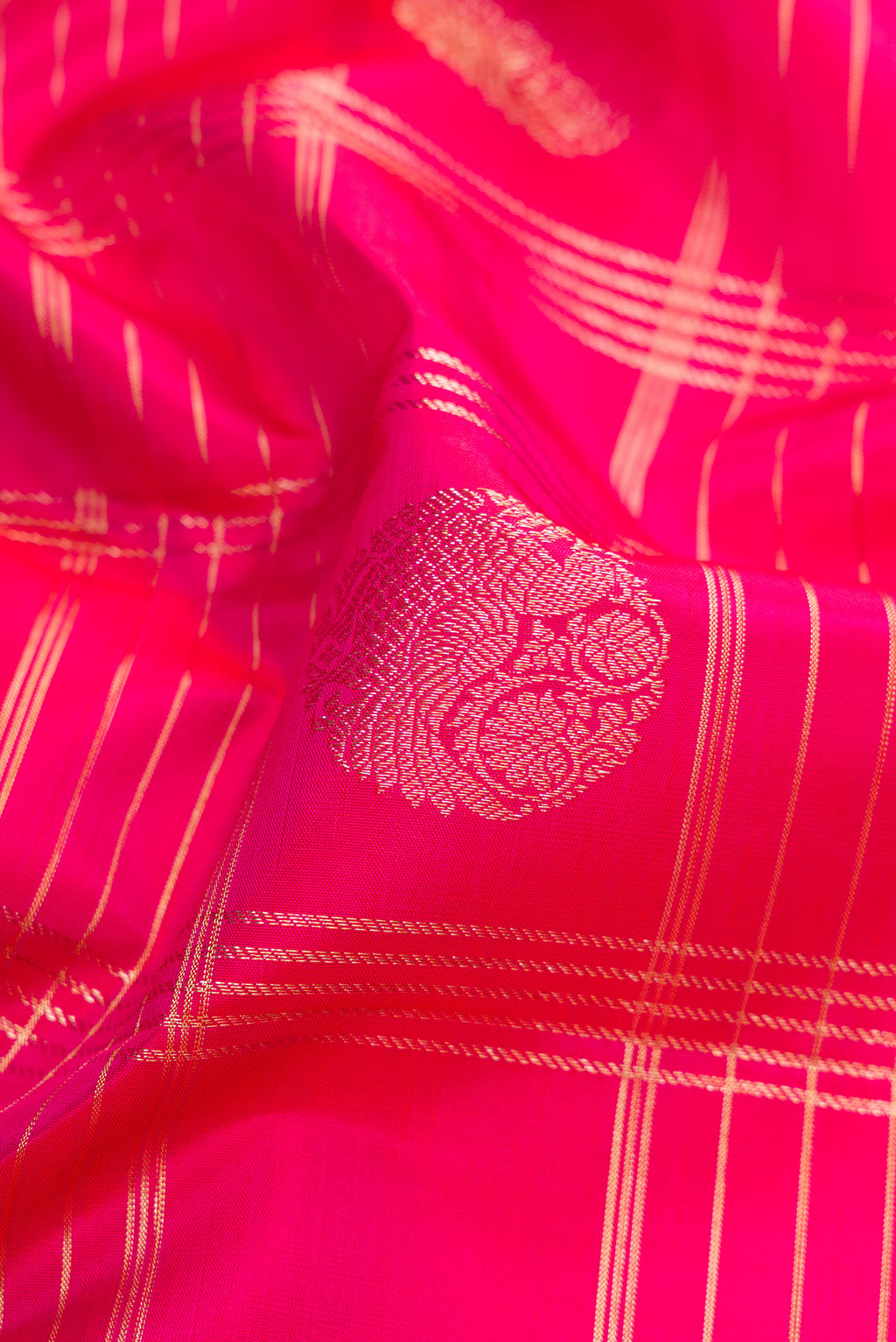 Close up of Rani Pink Kanchipuram Silk Saree with Checked design on the body and Zari Border.  displaying folds