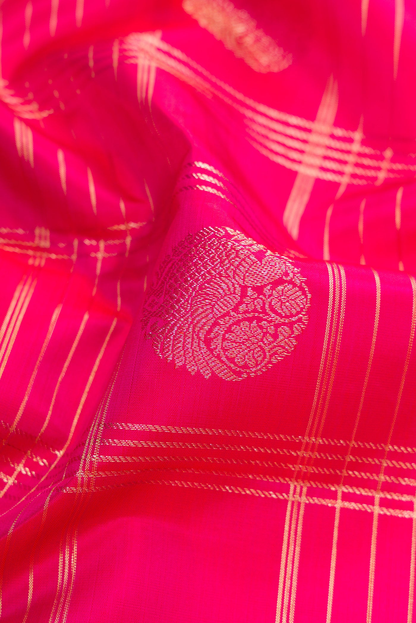 Close up of Rani Pink Kanchipuram Silk Saree with Checked design on the body and Zari Border.  displaying folds