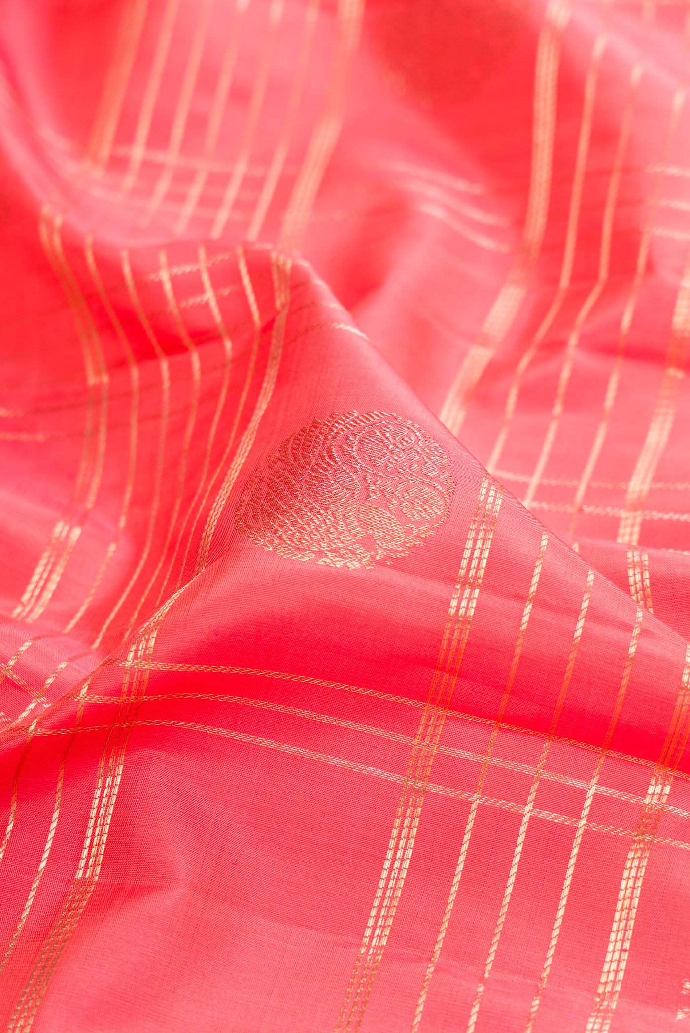Close up of Coral Kanchipuram Silk Saree with Checked design on the body and Zari Border.  displaying folds