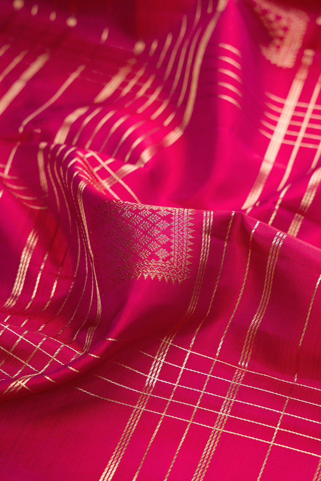 Close up of Pure Silk Dark Pink Kanchipuram Saree with Checked design on the body and Zari Border.  displaying folds