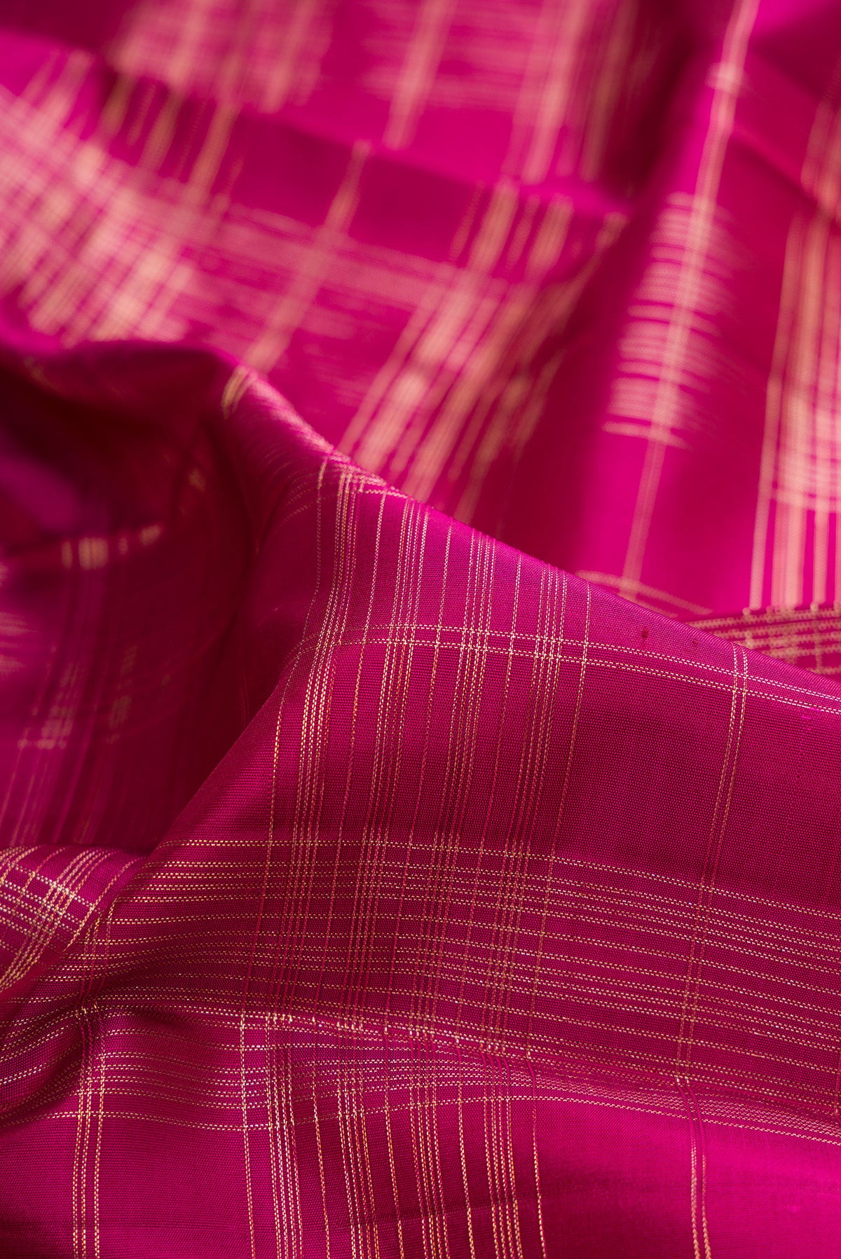 Close up of Pure Silk Dark Pink Kanchipuram Saree with Checked design on the body and Zari Border.  displaying folds