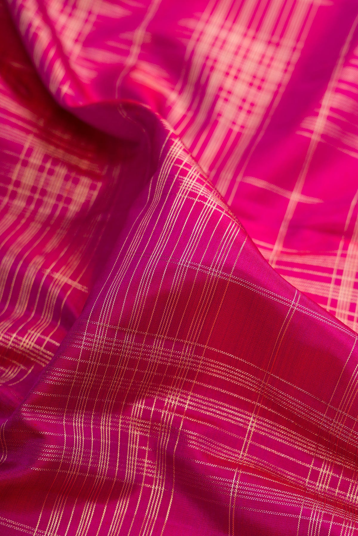 Close up of Pure Silk Dark Pink Kanchipuram Saree with Checked design on the body and Zari Border.  displaying folds