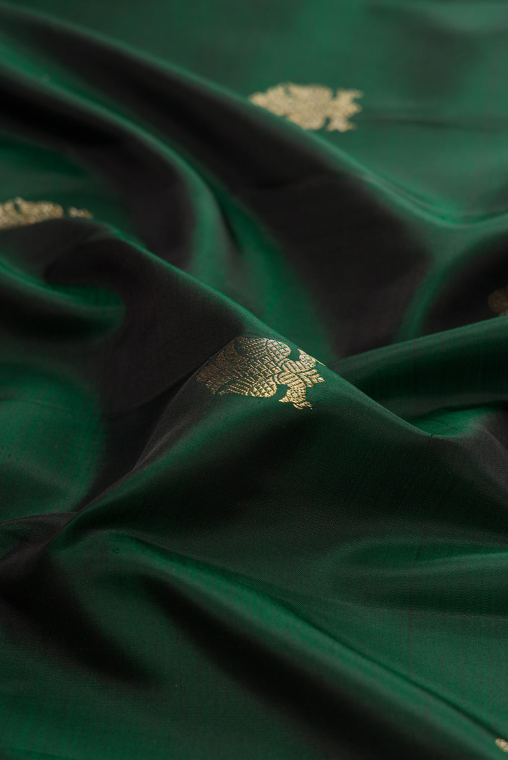 Close up of Pure Silk Bottle Green Kanchipuram Saree with Zari Butta on the body and Zari Border.  displaying folds