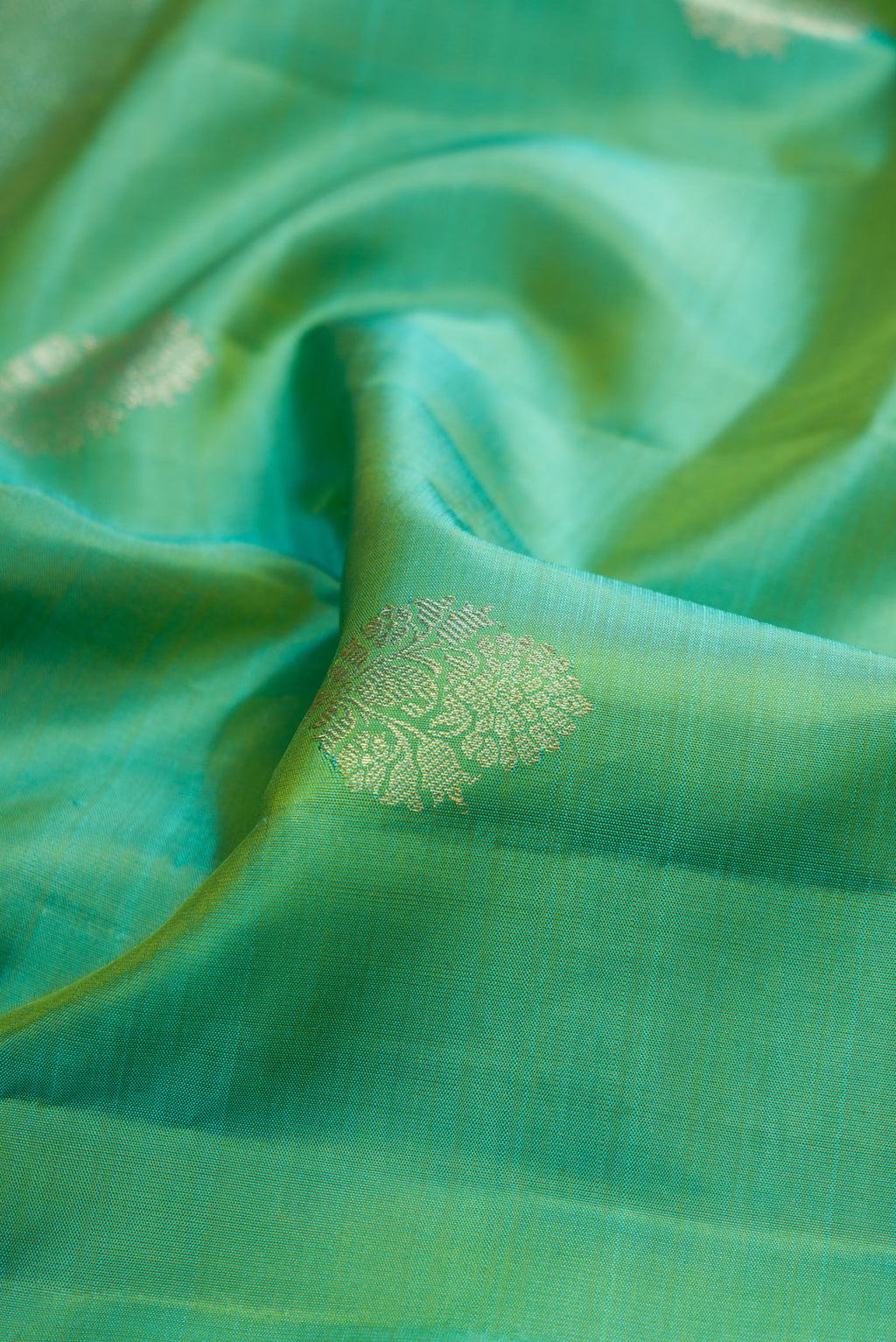 Close up of Sea Green Kanjivaram Silk Saree with Zari Butta on the body and Fancy Border.  displaying folds