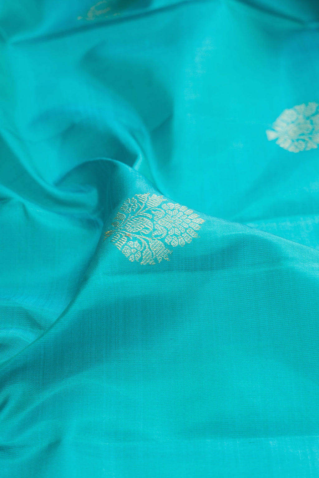 Close up of Sky Blue Kanjivaram Silk Saree with Zari Butta on the body and Fancy Border.  displaying folds