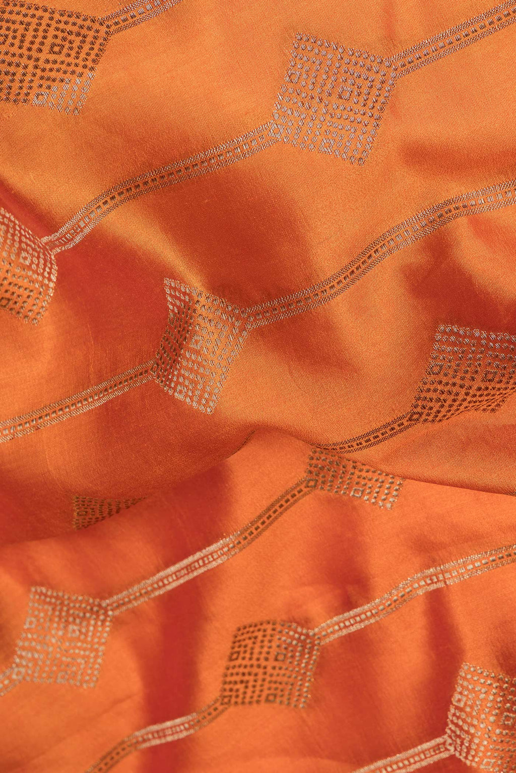 Close up of Orange Tussar Silk Saree with Zari Butta on the body and Zari Border.  displaying folds
