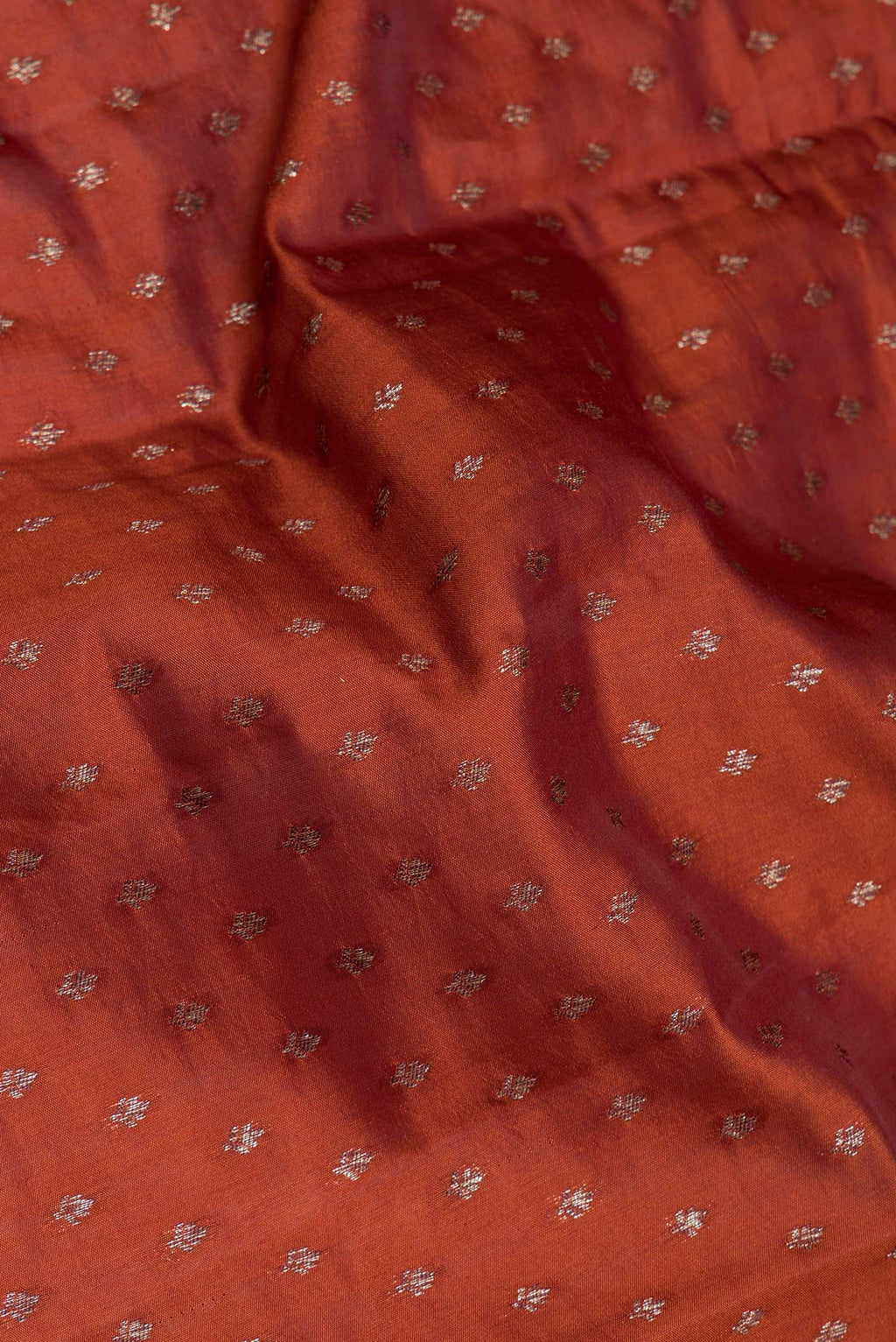 Close up of Rust Tussar Silk Saree with Zari Butta on the body and Zari Border.  displaying folds
