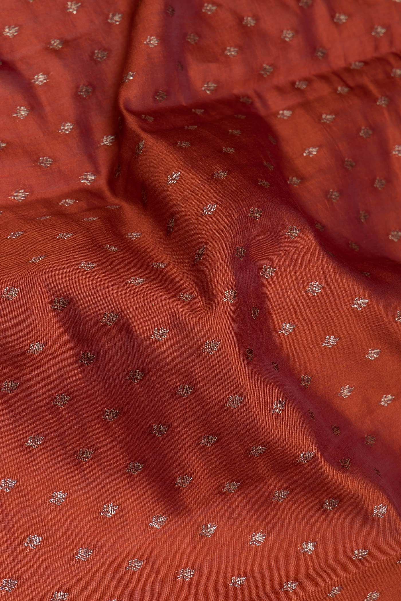 Close up of Rust Tussar Silk Saree with Zari Butta on the body and Zari Border.  displaying folds