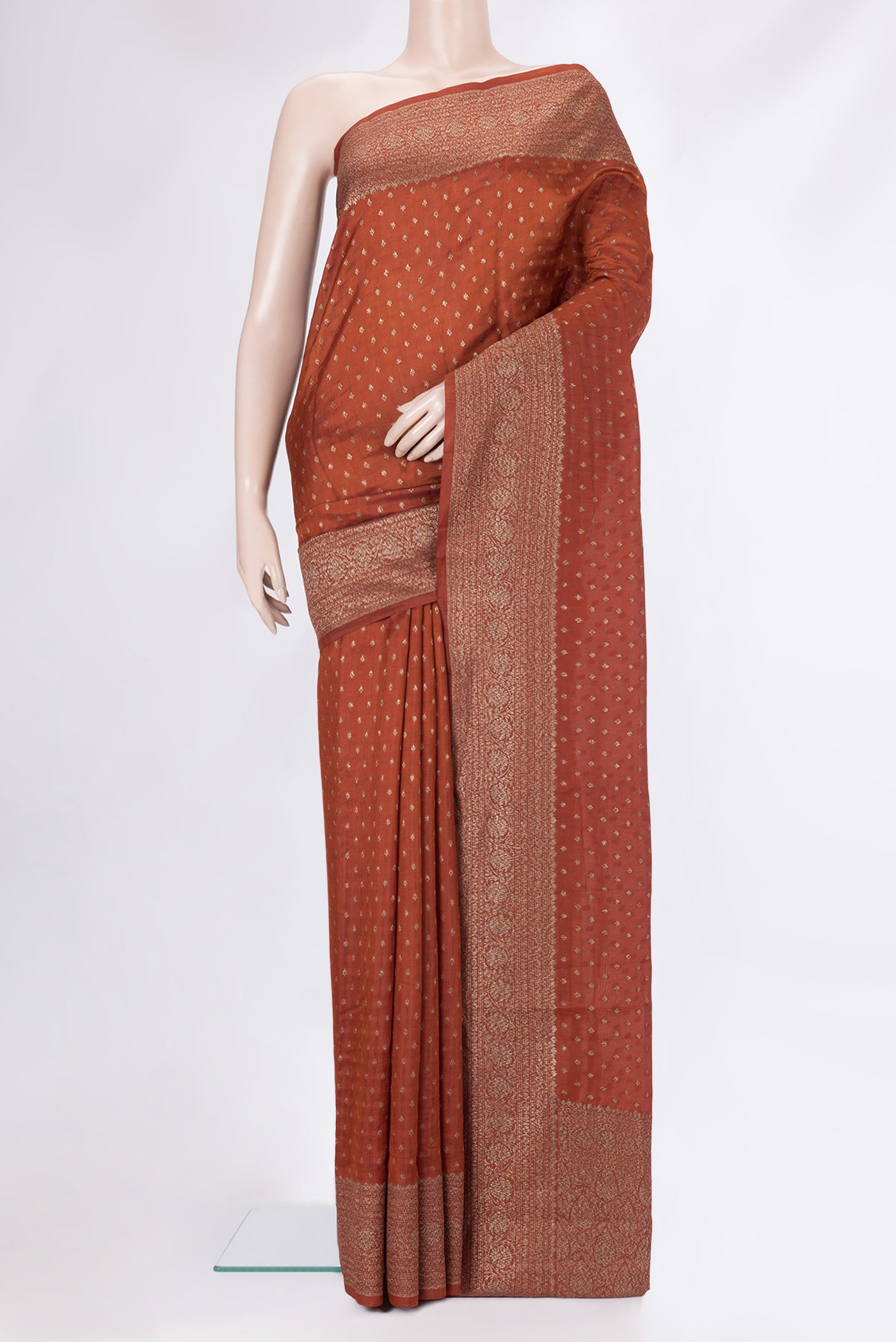 Rust Tussar Silk Saree with Zari Butta on the body and Zari Border.  displayed on a mannequin