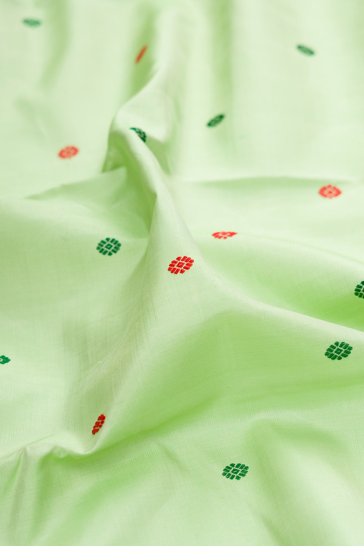 Close up of Pure Silk Pure Zari Pista Green Dual Tone Kanchipuram Saree with Thread Butta on the body and Zari Border.  displaying folds