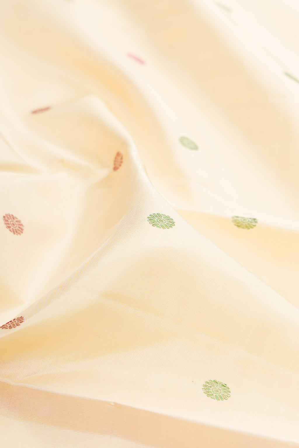 Close up of Cream Kanjivaram Silk Saree with Thread Butta on the body and Fancy Border.  displaying folds