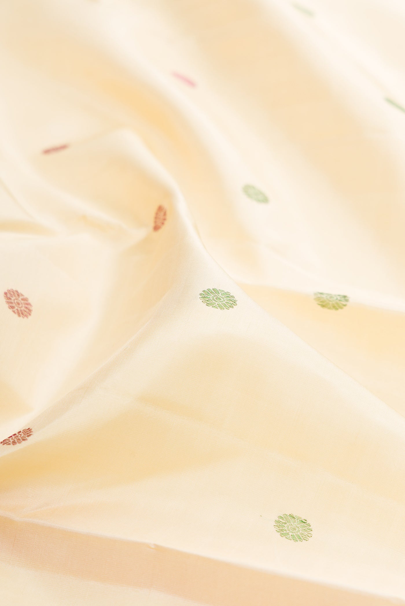 Close up of Cream Kanjivaram Silk Saree with Thread Butta on the body and Fancy Border.  displaying folds