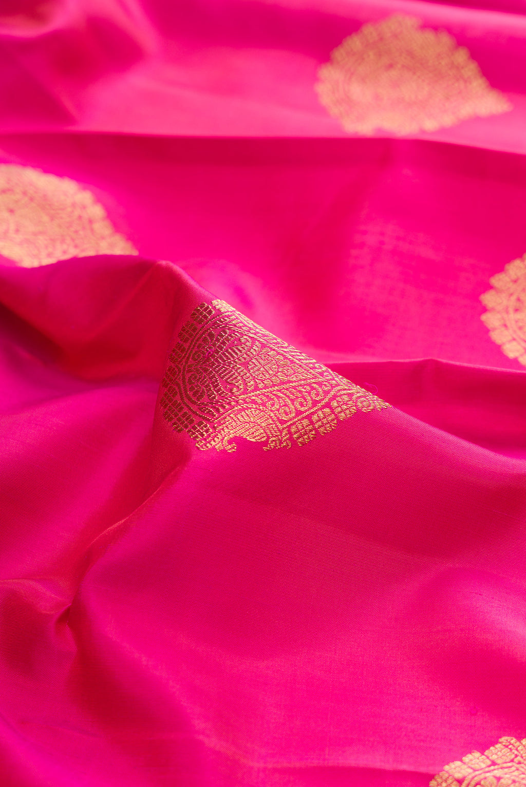 Close up of Pure Silk Pure Zari Pink Kanjivaram Saree with Zari Butta on the body and Zari Border.  displaying folds