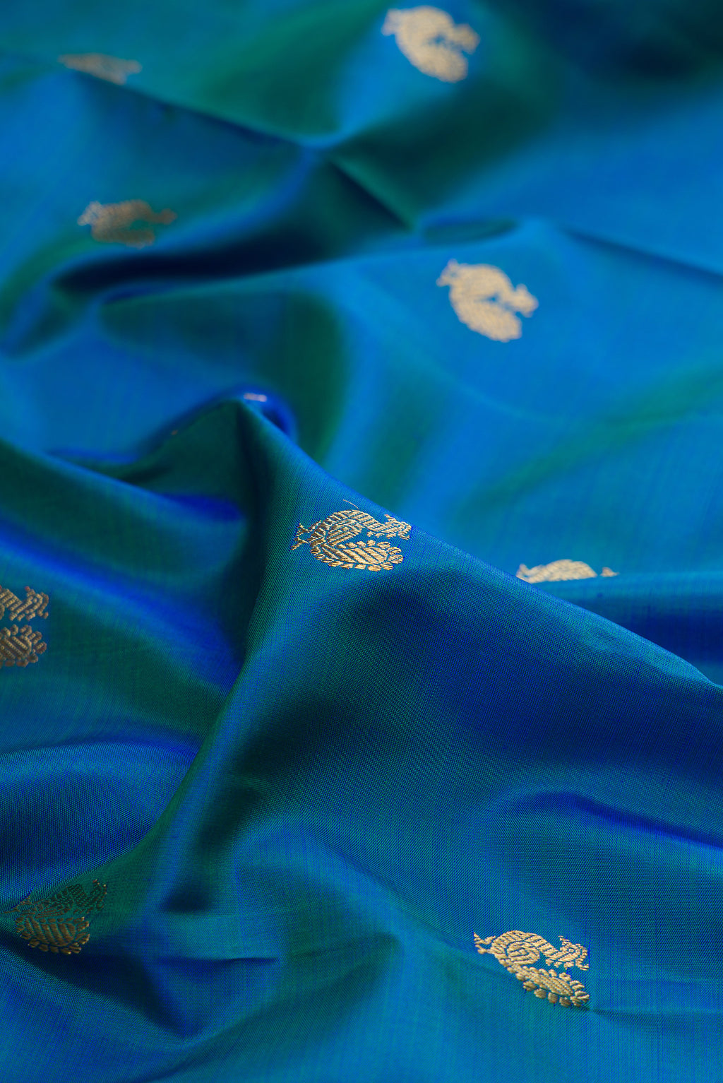Close up of Pure Silk Pure Zari Peacock Blue Kanjivaram Saree with Zari Butta on the body and Zari Border.  displaying folds