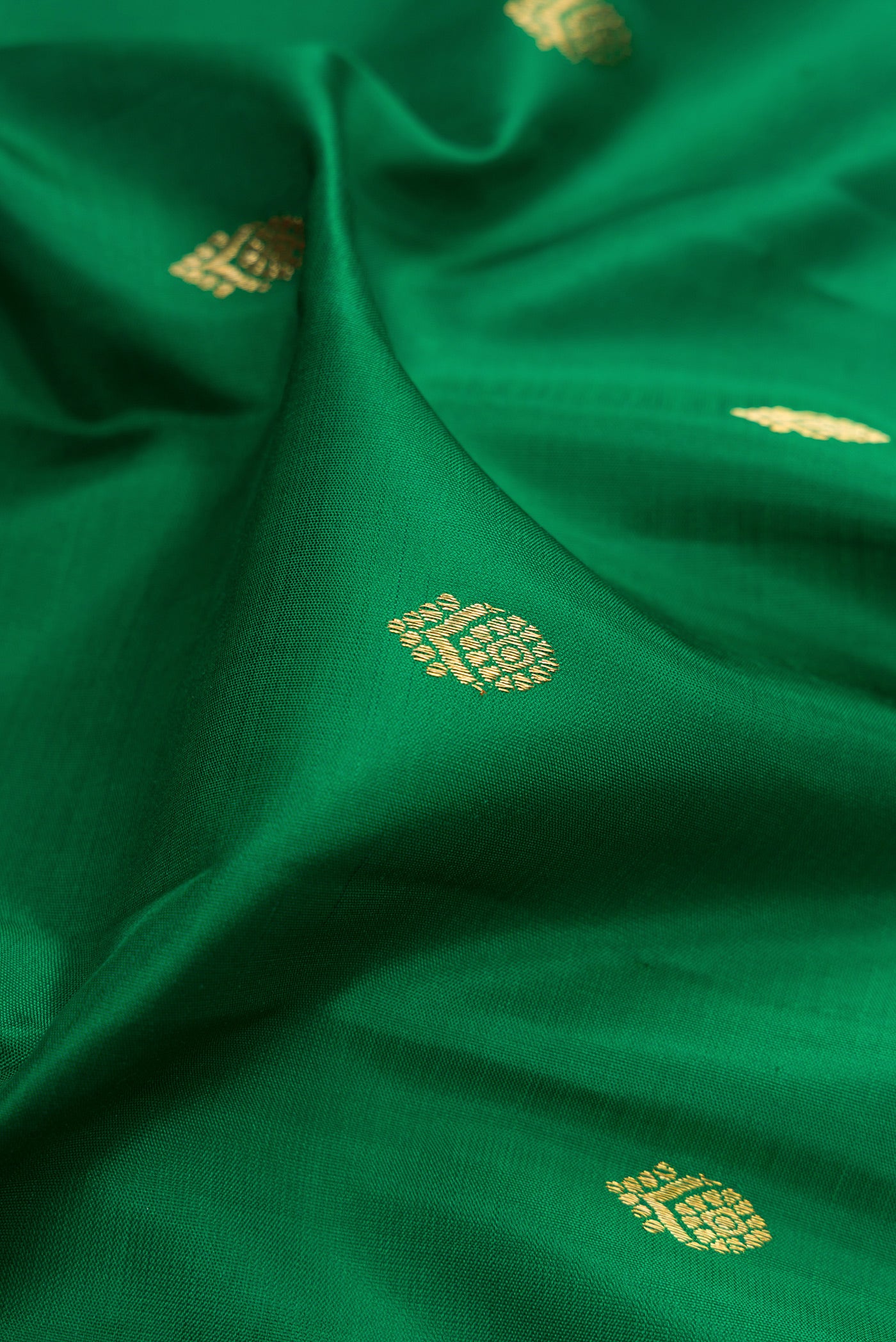 Close up of Pure Silk Pure Zari Green Kanjivaram Saree with Zari Butta on the body and Zari Border.  displaying folds
