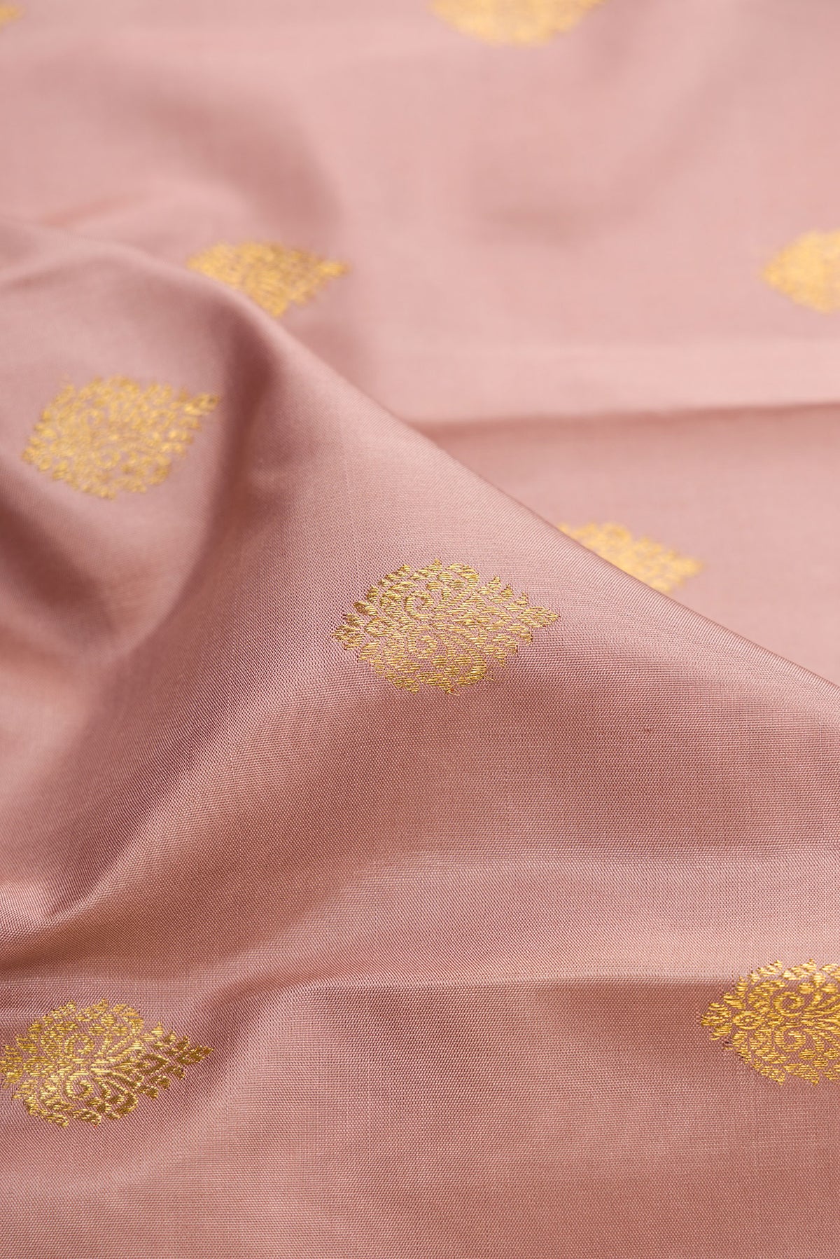 Close up of Pure Silk Pure Zari Rose Gold Kanjivaram Saree with Zari Butta on the body and Fancy Border.  displaying folds