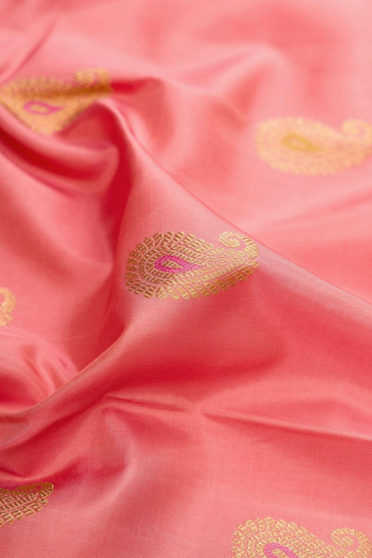 Close up of Pure Silk Pure Zari Coral Kanjivaram Saree with Zari And Thread Butta on the body and Fancy Border.  displaying folds