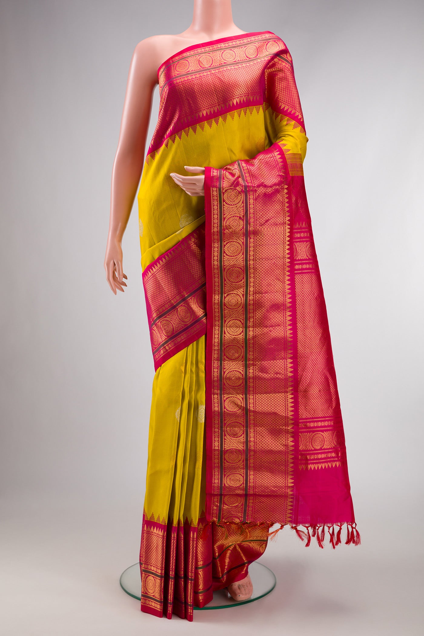 Mustard Gadwal Silk Saree with Zari Butta on the body and Temple Border.  displayed on a mannequin