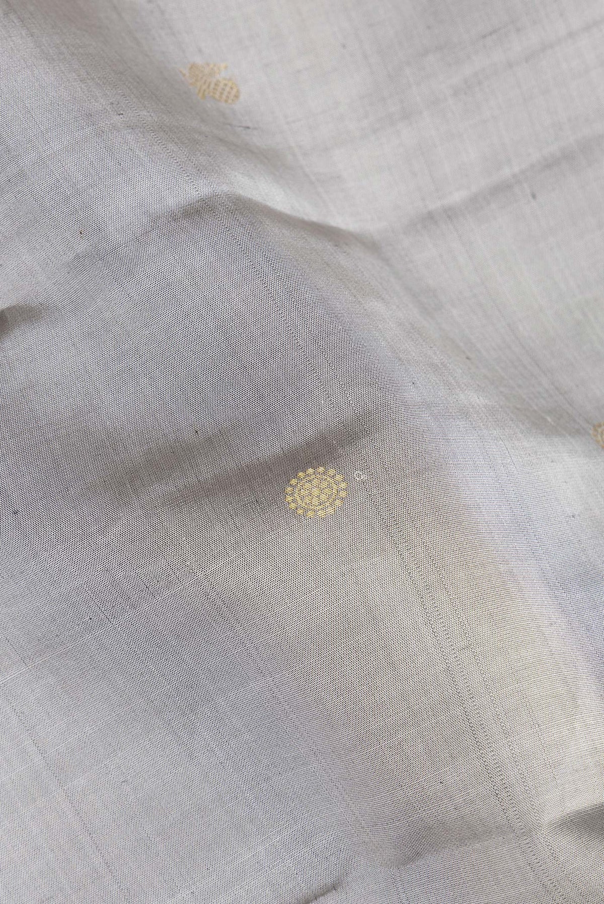 Close up of Pure Silk Grey Dual Tone Kanchipuram Saree with Zari Butta on the body and Zari Border.  displaying folds