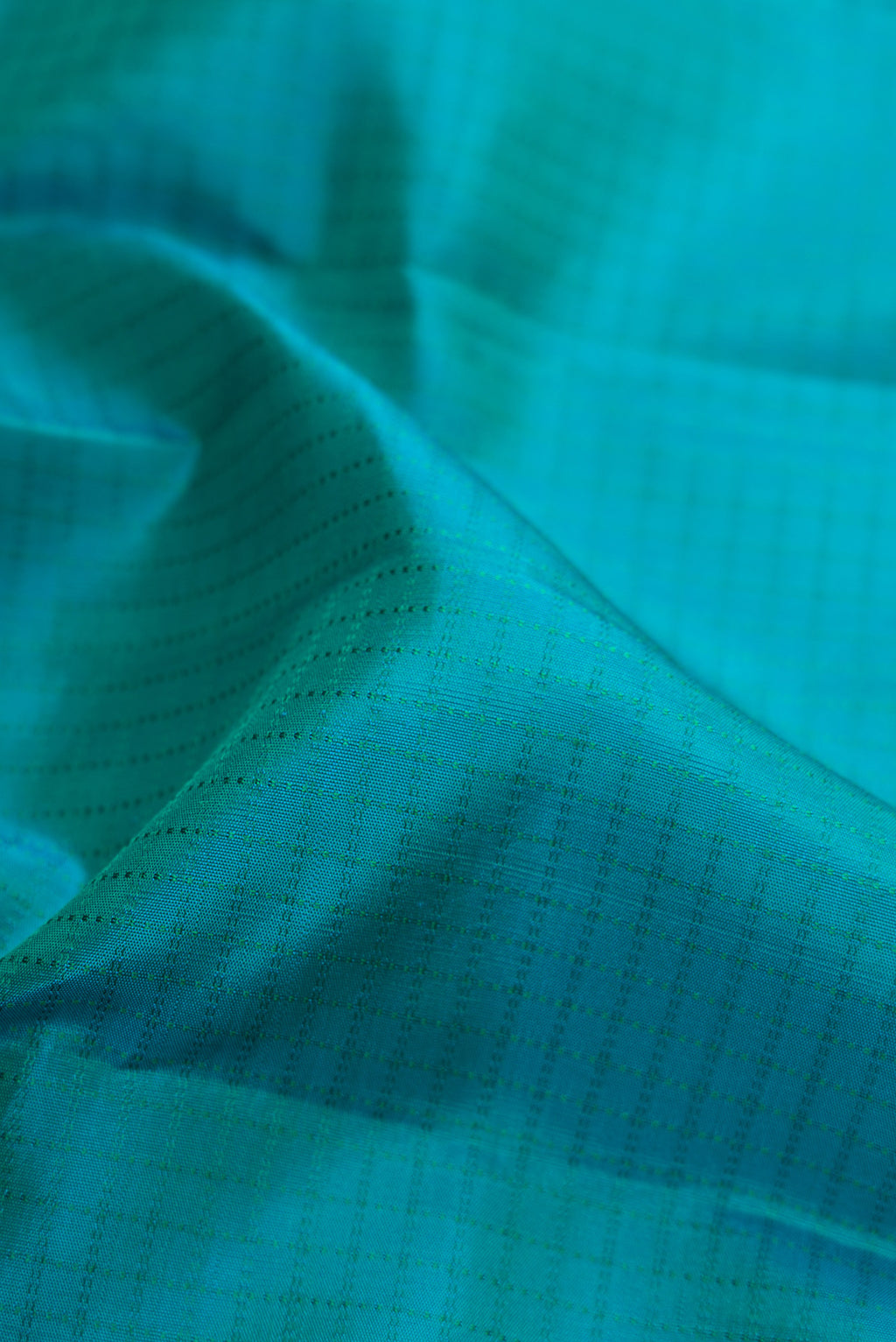 Close up of Peacock Blue Dual Tone Kanchipuram Silk Saree with Checked design on the body and Zari Border.  displaying folds