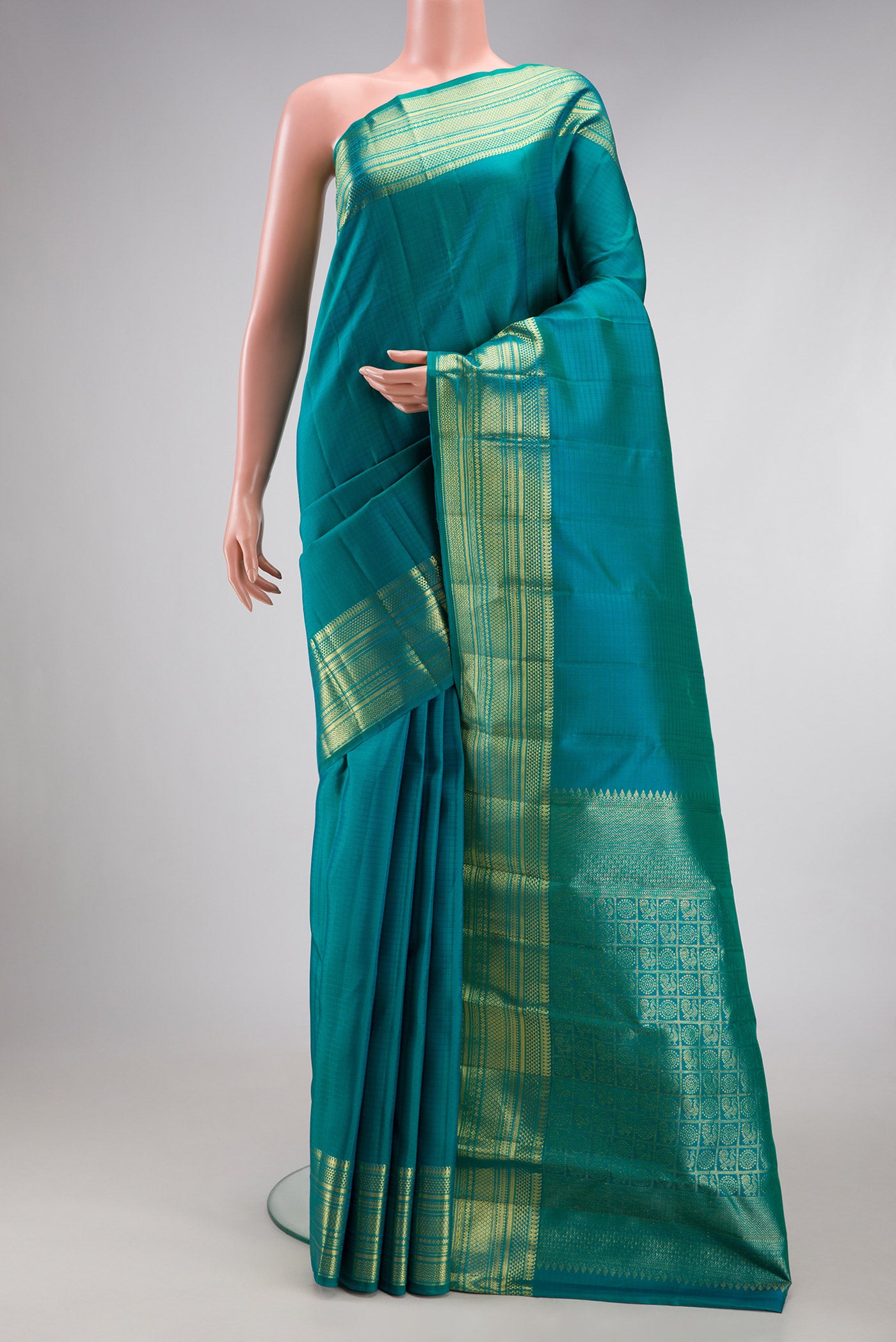 Peacock Blue Dual Tone Kanchipuram Silk Saree with Checked design on the body and Zari Border.  displayed on a mannequin