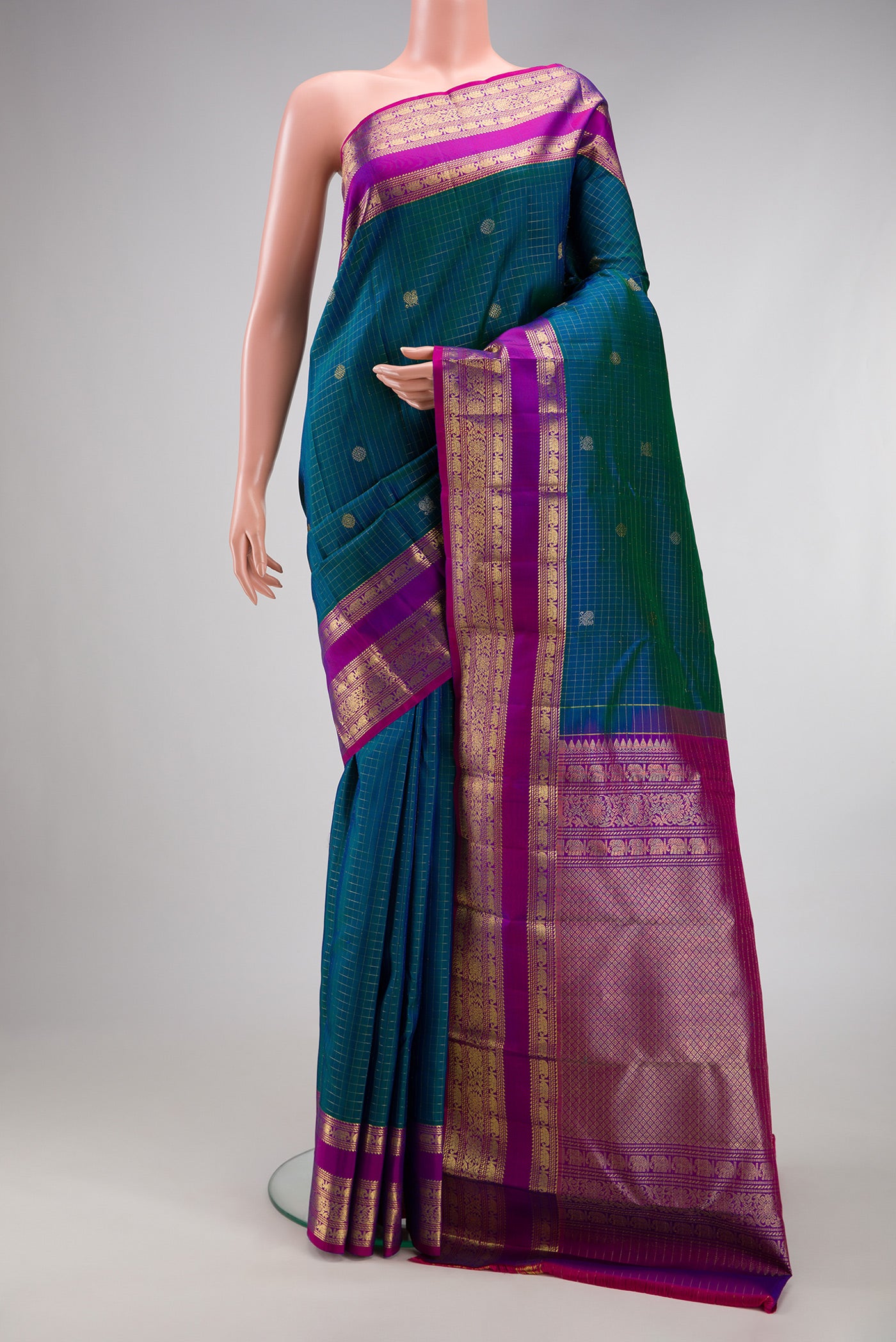 Peacock Blue Dual Tone Kanjivaram Silk Saree with Checked design on the body and Fancy Border.  displayed on a mannequin