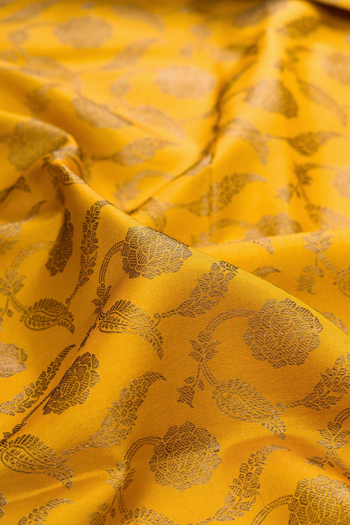 Close up of Pure Silk Mustard Kanjivaram Saree with Zari Brocade on the body and Fancy Border.  displaying folds