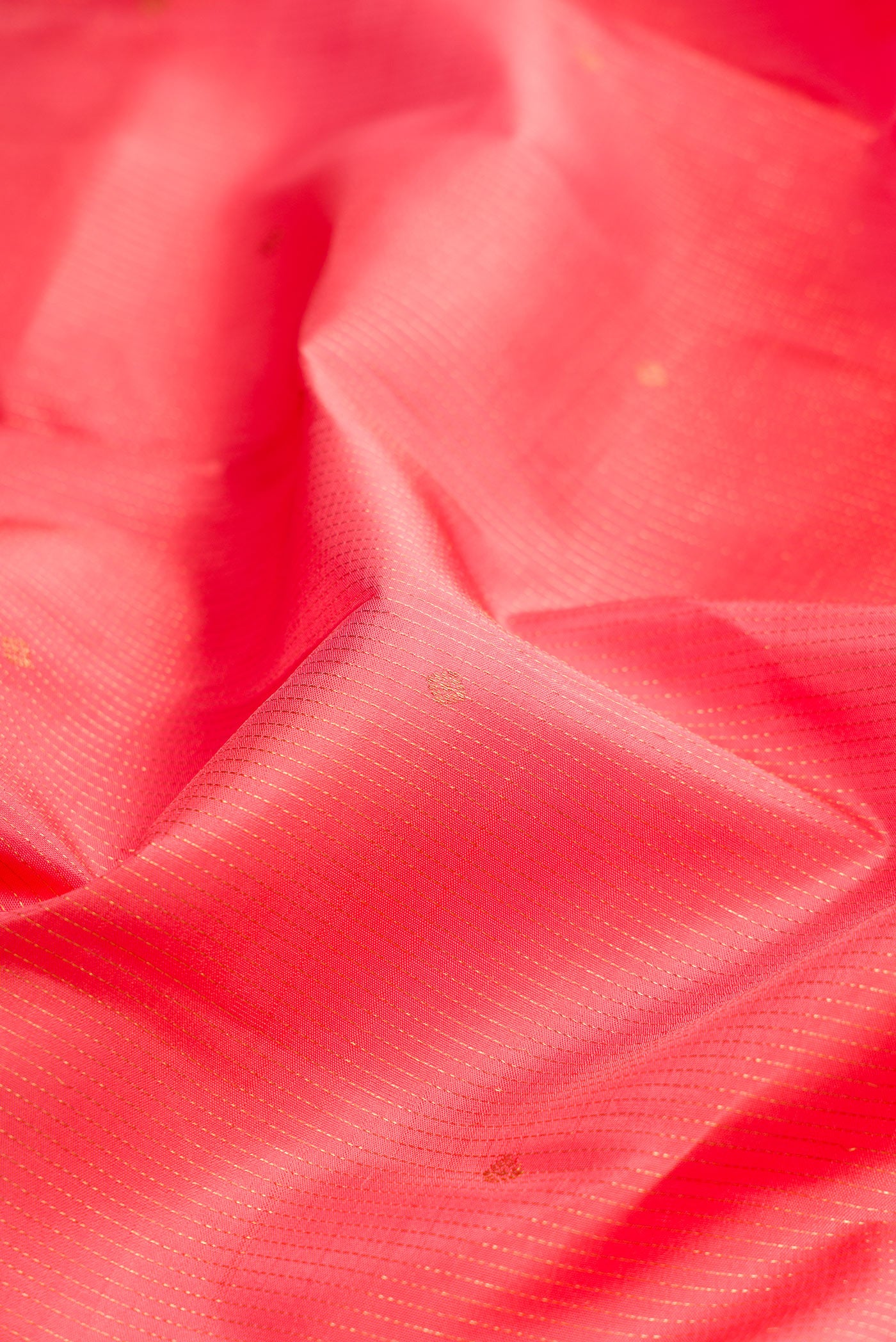 Close up of Coral Kanjivaram Silk Saree with Stripes on the body and Zari Border.  displaying folds
