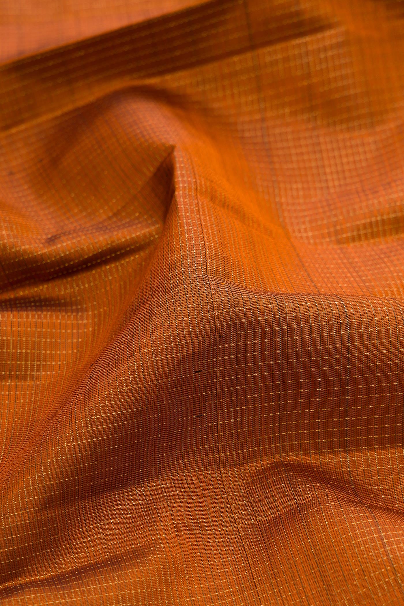 Close up of Rust Kanjivaram Silk Saree with Checked design on the body and Fancy Border.  displaying folds