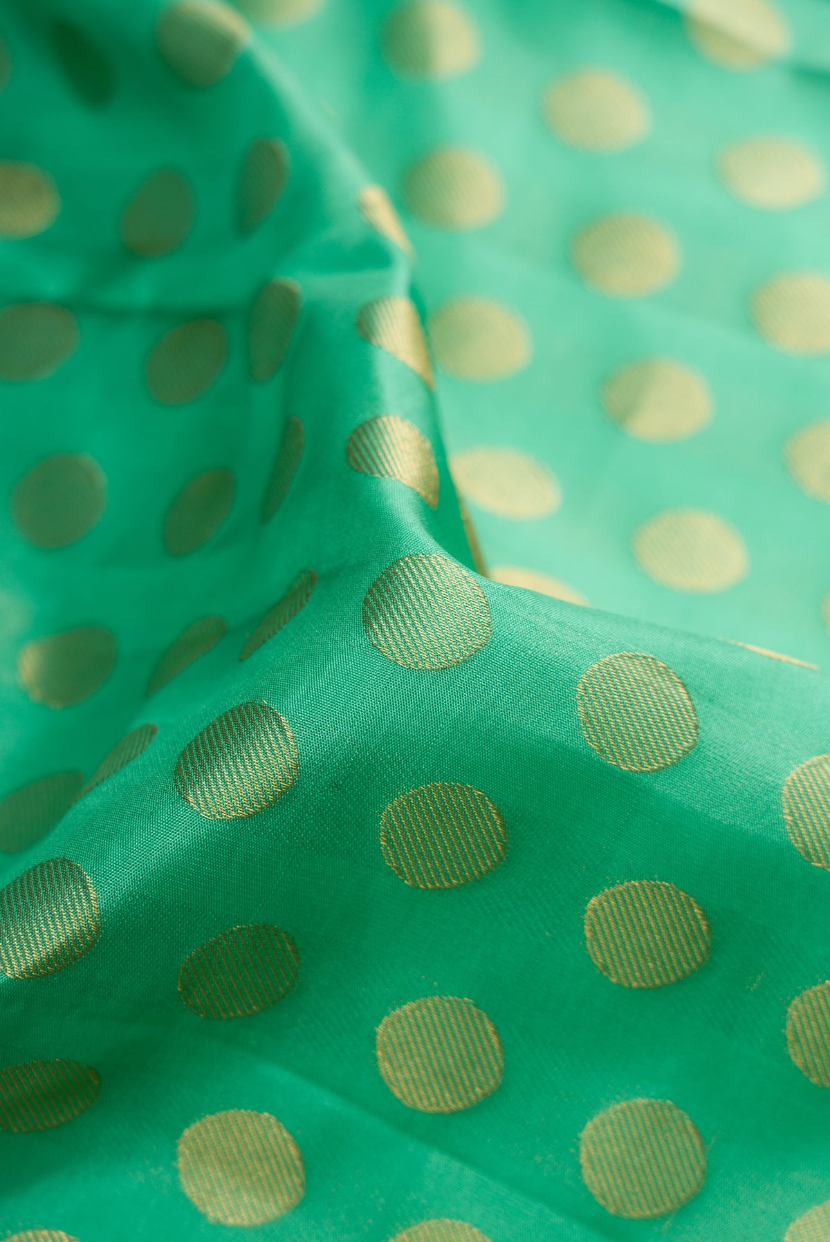 Close up of Pure Silk Green Kanchipuram Saree with Zari Butta on the body and Zari Border.  displaying folds