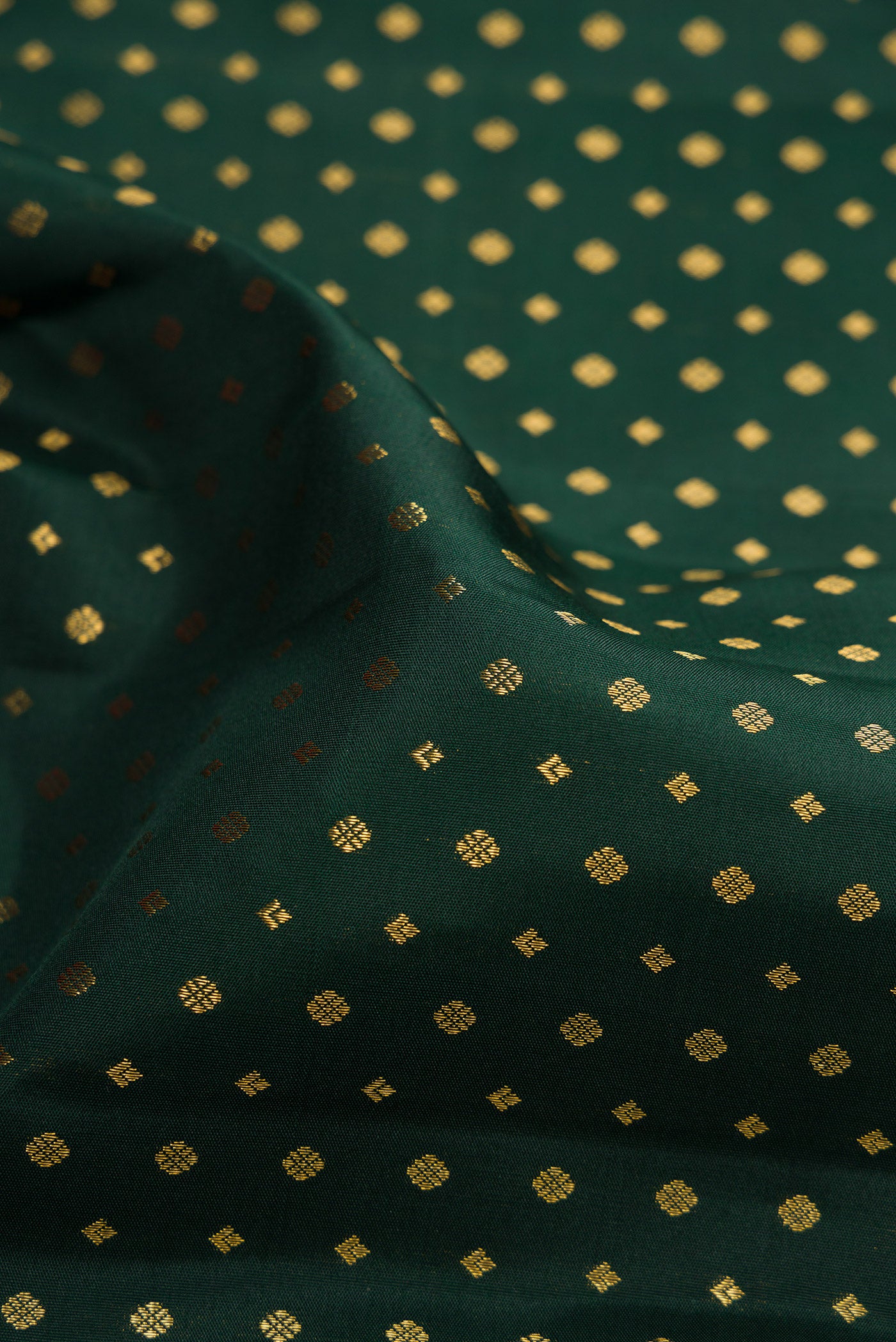 Close up of Bottle Green Kanjivaram Silk Saree with Zari Butta on the body and Fancy Border.  displaying folds