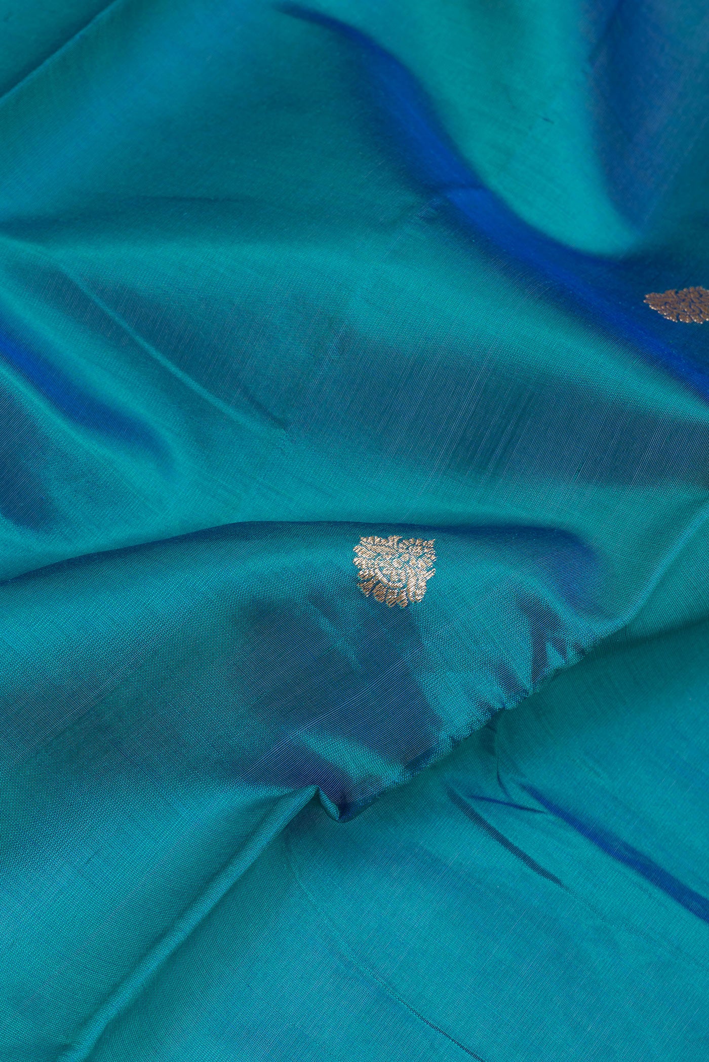 Close up of Peacock Blue Banarasi Silk Saree with Zari Butta on the body and Zari Border.  displaying folds