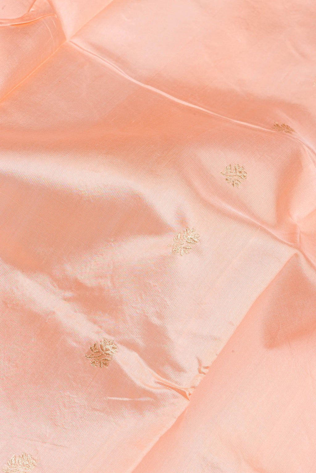 Close up of Peach Banarasi Silk Saree with Zari Butta on the body and Zari Border.  displaying folds