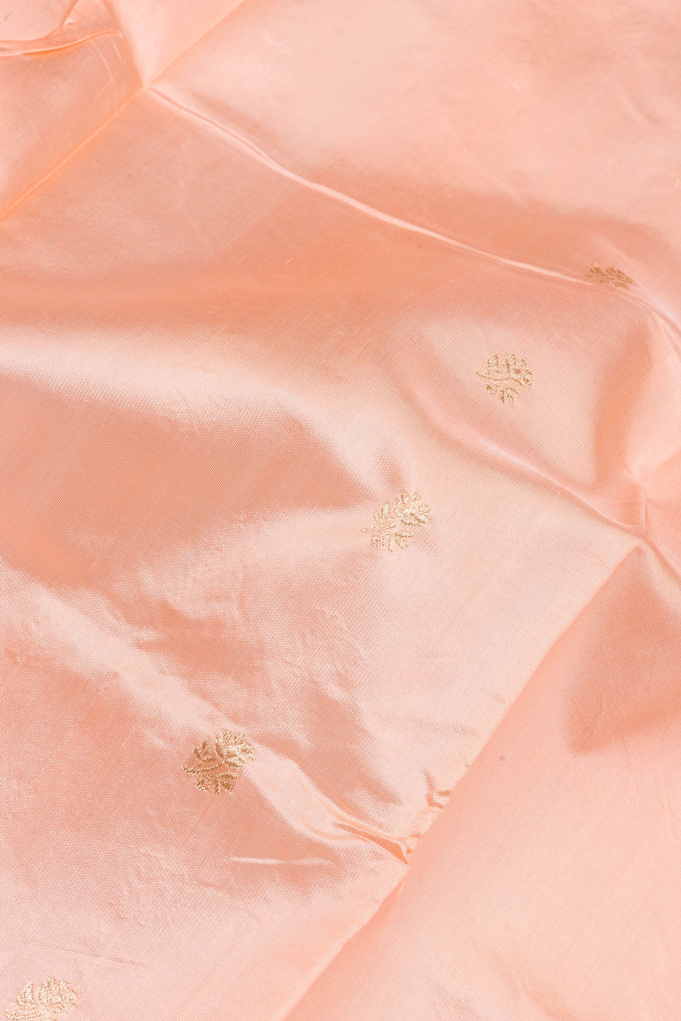 Close up of Peach Banarasi Silk Saree with Zari Butta on the body and Zari Border.  displaying folds