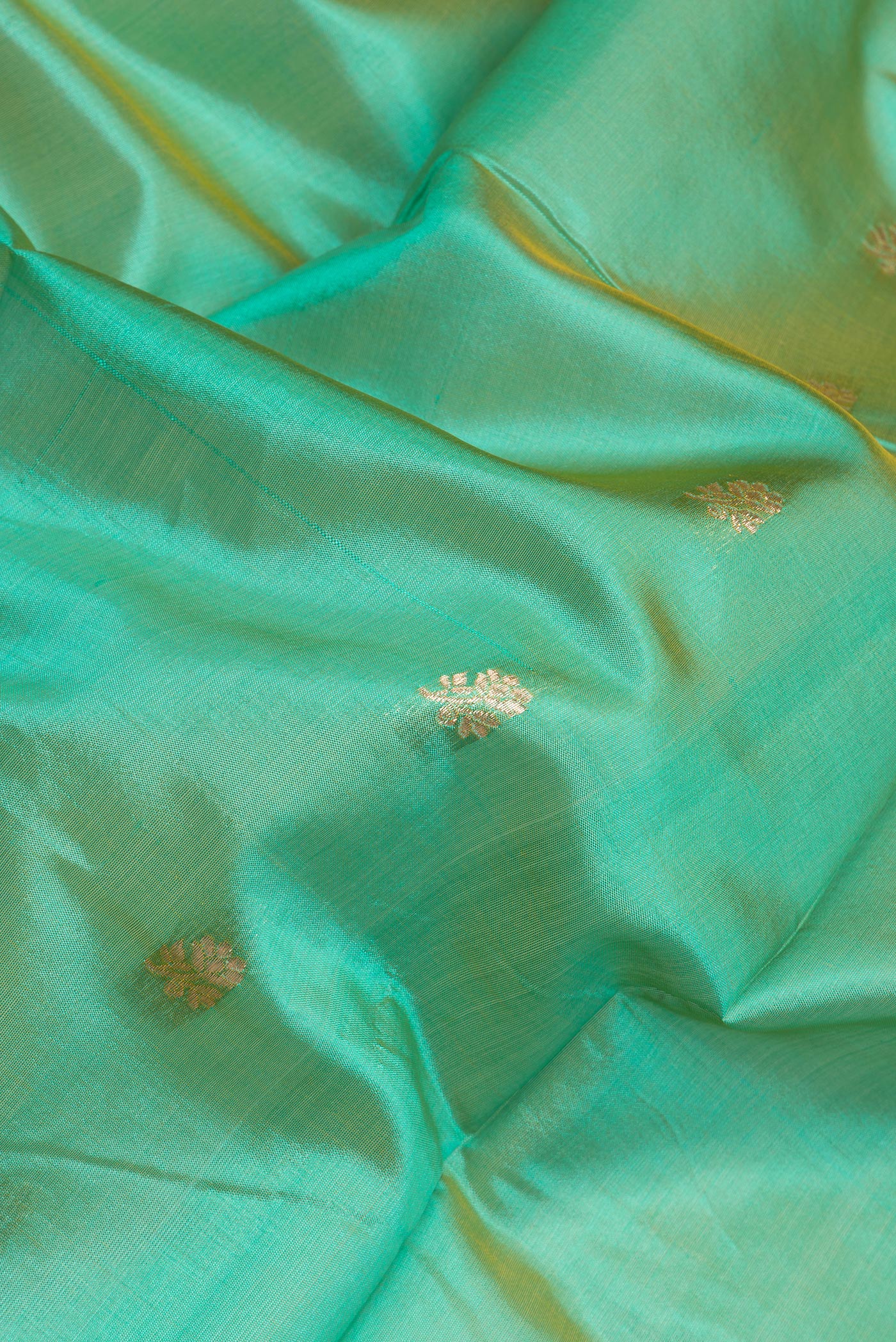 Close up of Sea Green Dual Tone Banarasi Silk Saree with Zari Butta on the body and Zari Border.  displaying folds