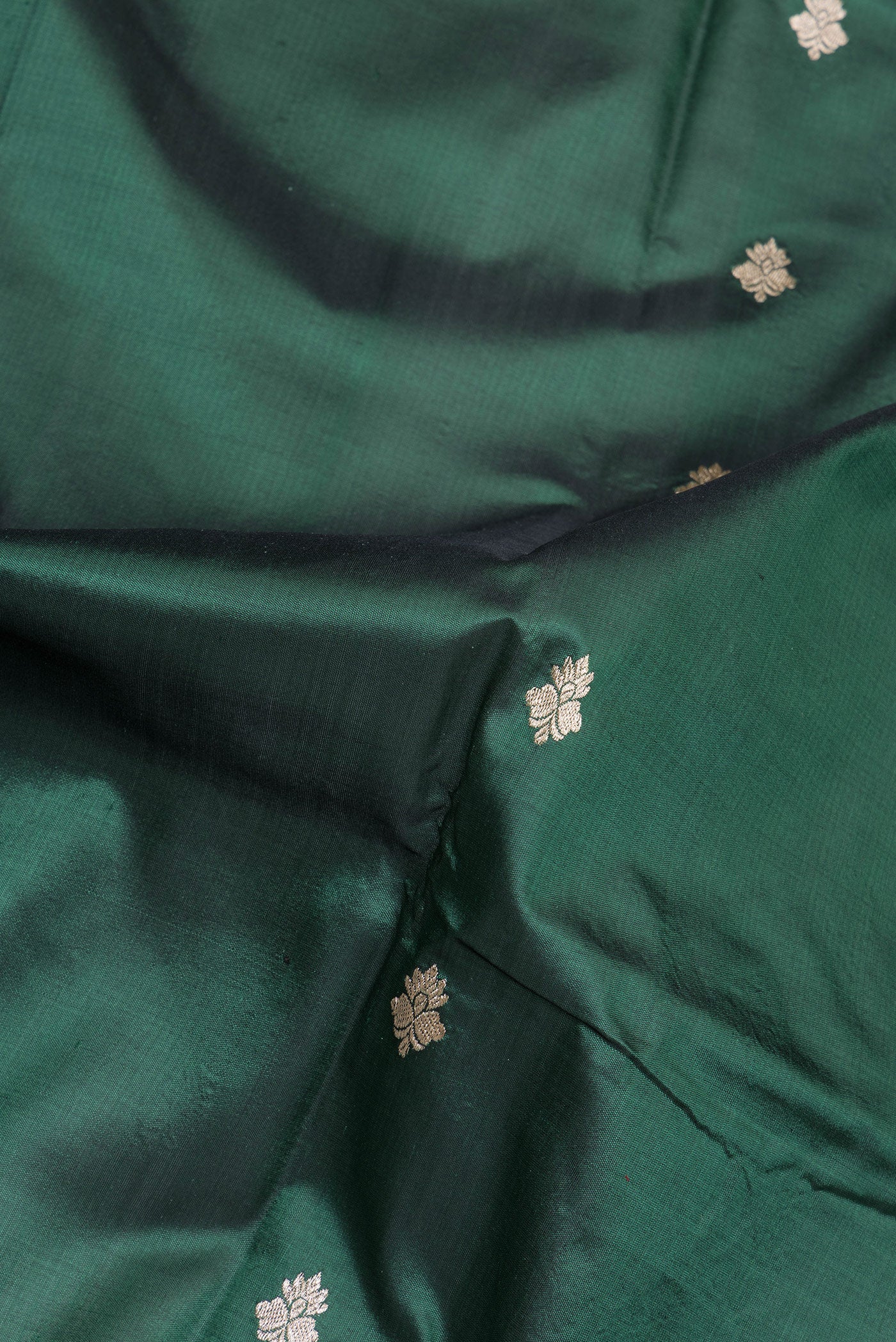 Close up of Bottle Green Banarasi Silk Saree with Zari Butta on the body and Zari Border.  displaying folds