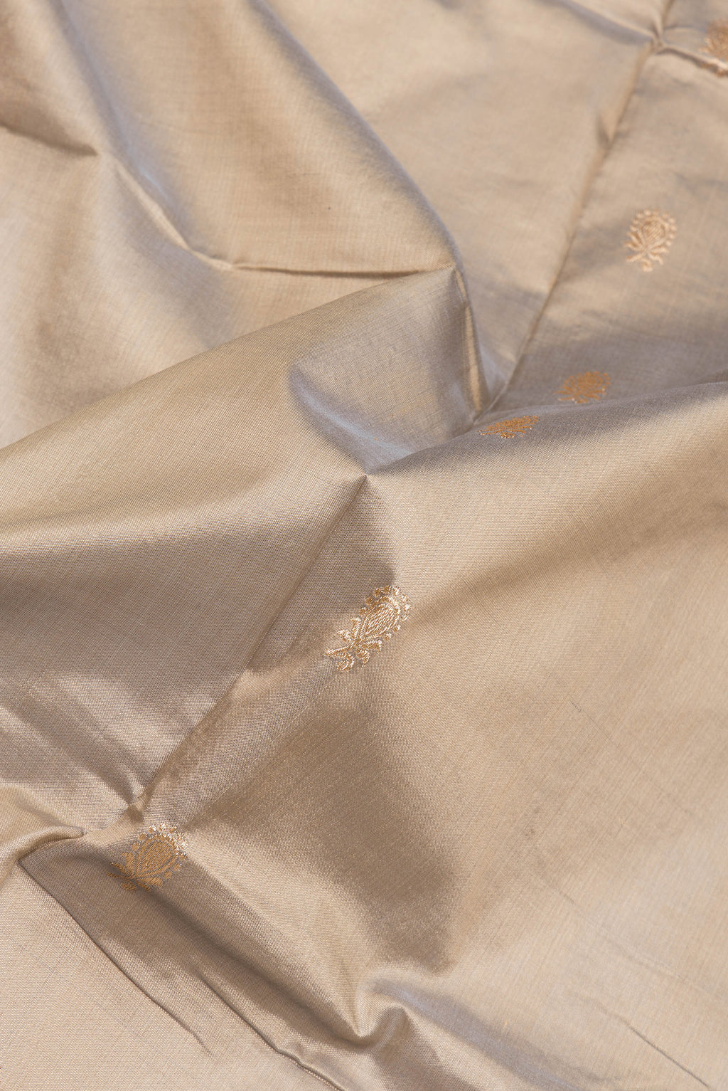 Close up of Beige Dual Tone Banarasi Silk Saree with Zari Butta on the body and Zari Border.  displaying folds