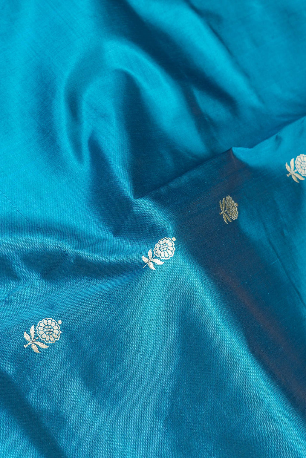 Close up of Peacock Blue Banarasi Silk Saree with Thread Butta on the body and Thread Border.  displaying folds