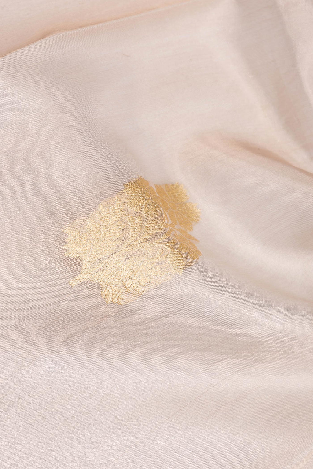 Close up of Rose Gold Organza Saree with Zari Butta on the body and Zari Border.  displaying folds