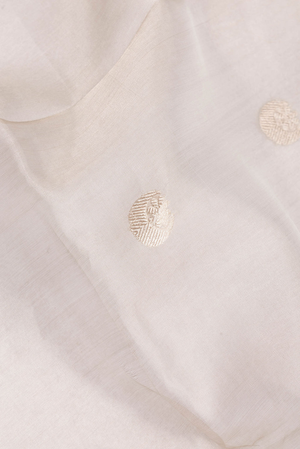Close up of Beige Organza Saree with Zari Butta on the body and Zari Border.  displaying folds