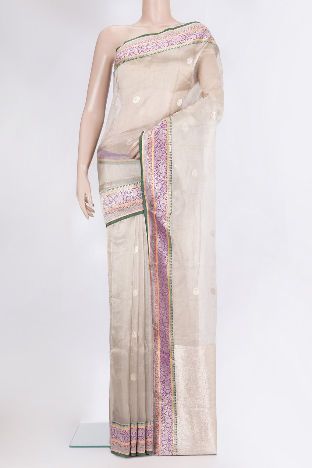 Beige Organza Saree with Zari Butta on the body and Zari Border.  displayed on a mannequin