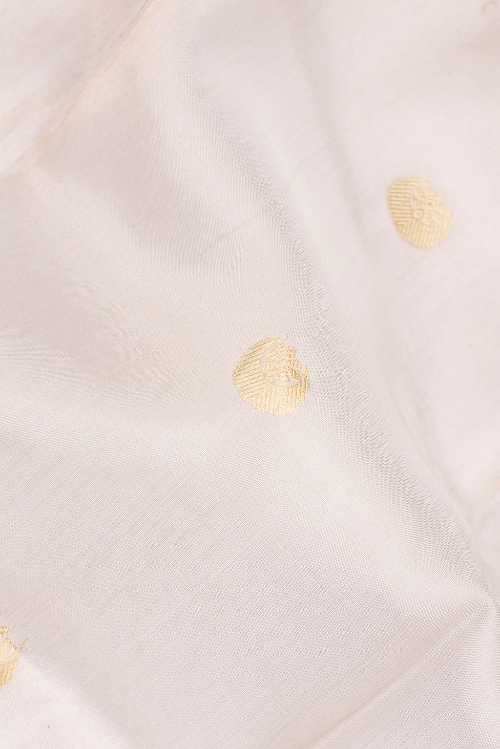 Close up of Beige Organza Saree with Zari Butta on the body and Zari Border.  displaying folds
