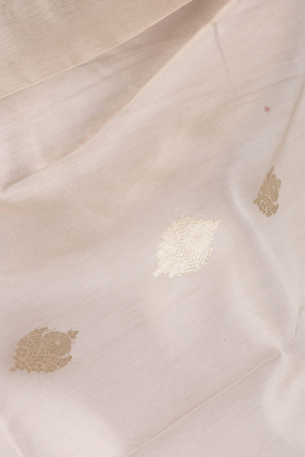 Close up of Beige Organza Saree with Zari Butta on the body and Zari Border.  displaying folds