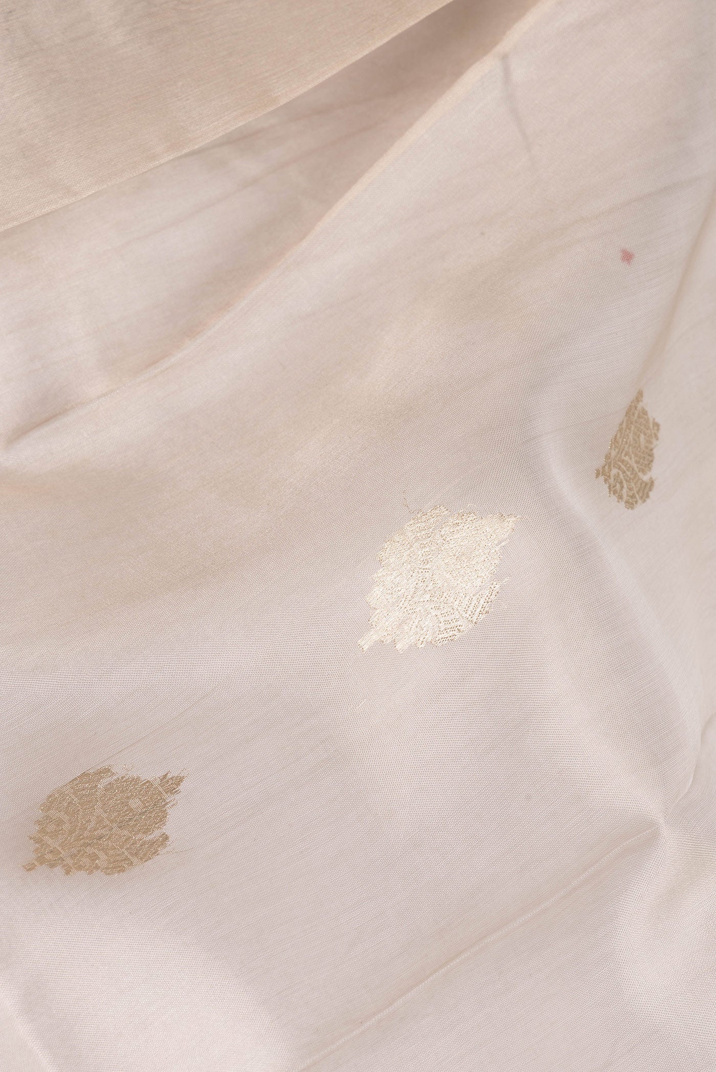 Close up of Beige Organza Saree with Zari Butta on the body and Zari Border.  displaying folds