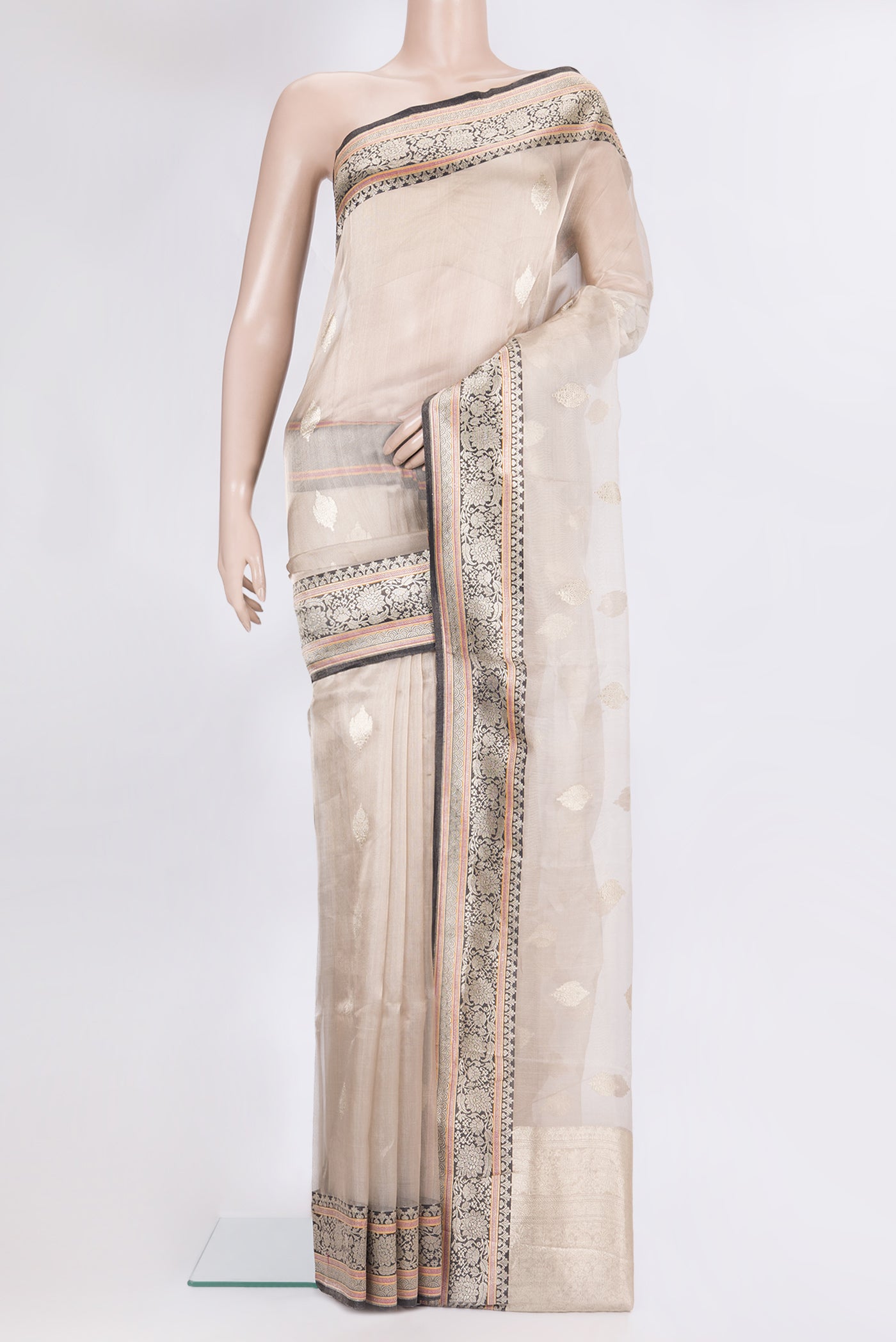 Beige Organza Saree with Zari Butta on the body and Zari Border.  displayed on a mannequin