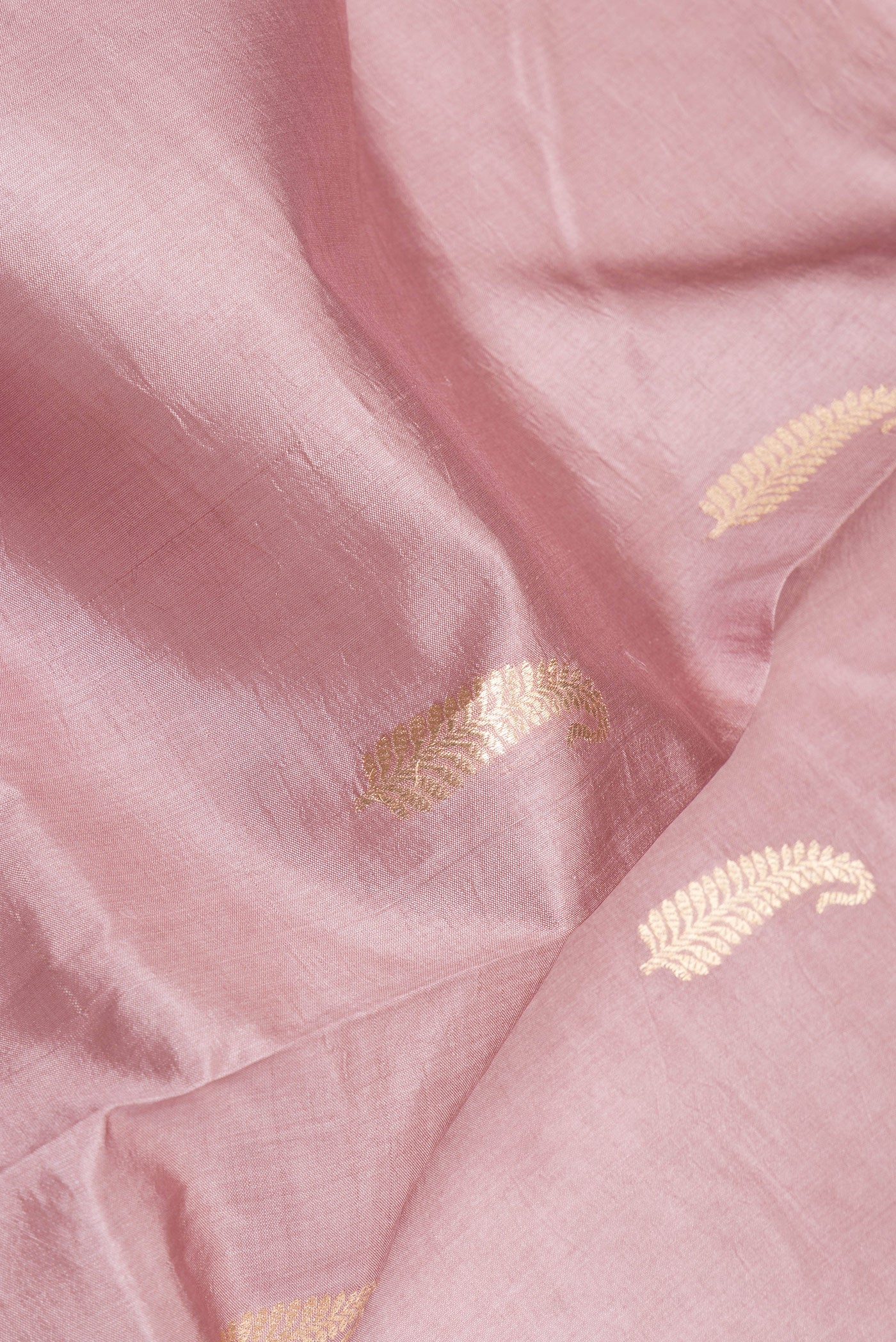 Close up of Rose Gold Banarasi Silk Saree with Zari Butta on the body and Zari Border.  displaying folds