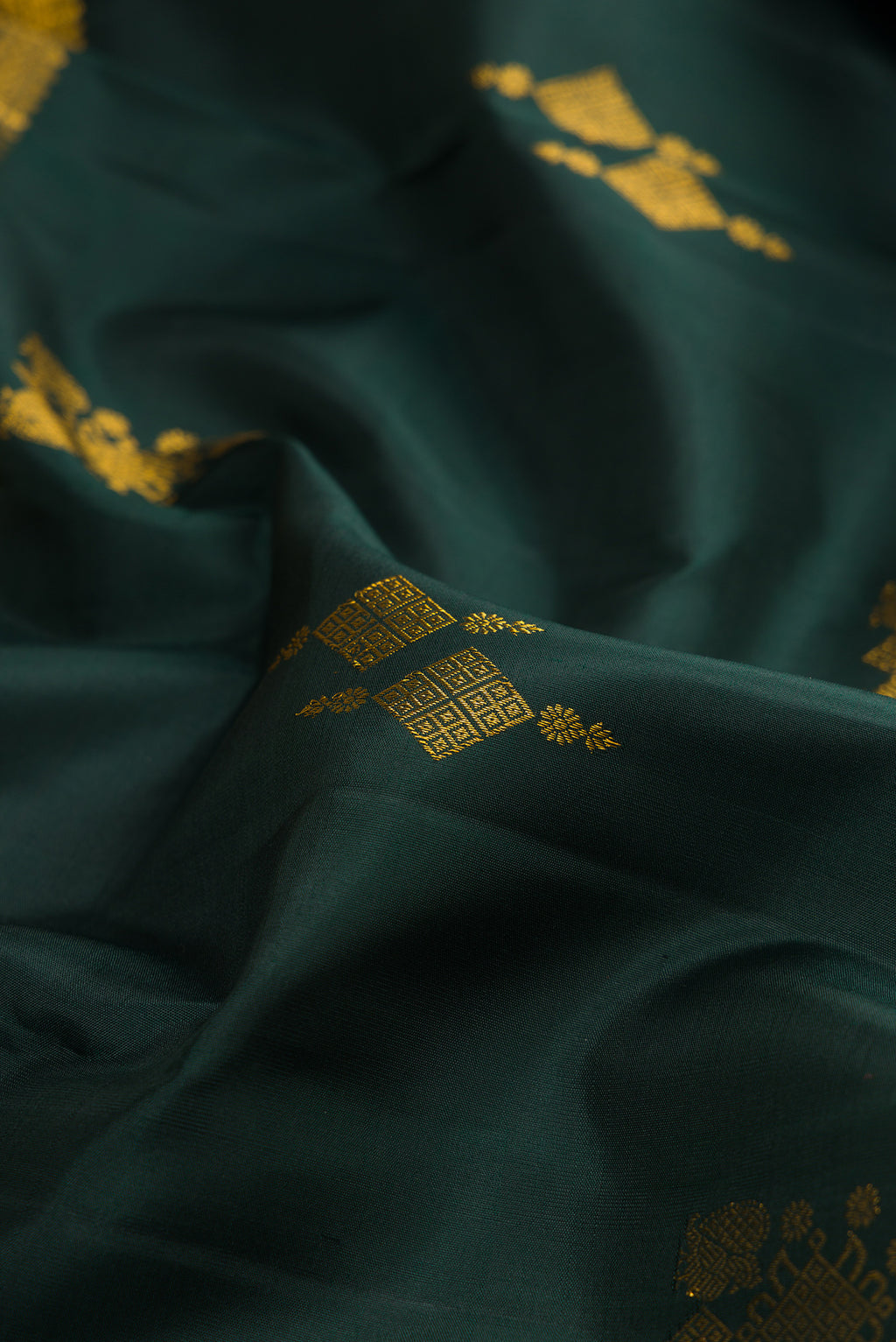 Close up of Pure Silk Bottle Green Kanjivaram Saree with Zari Butta on the body and Zari Border.  displaying folds