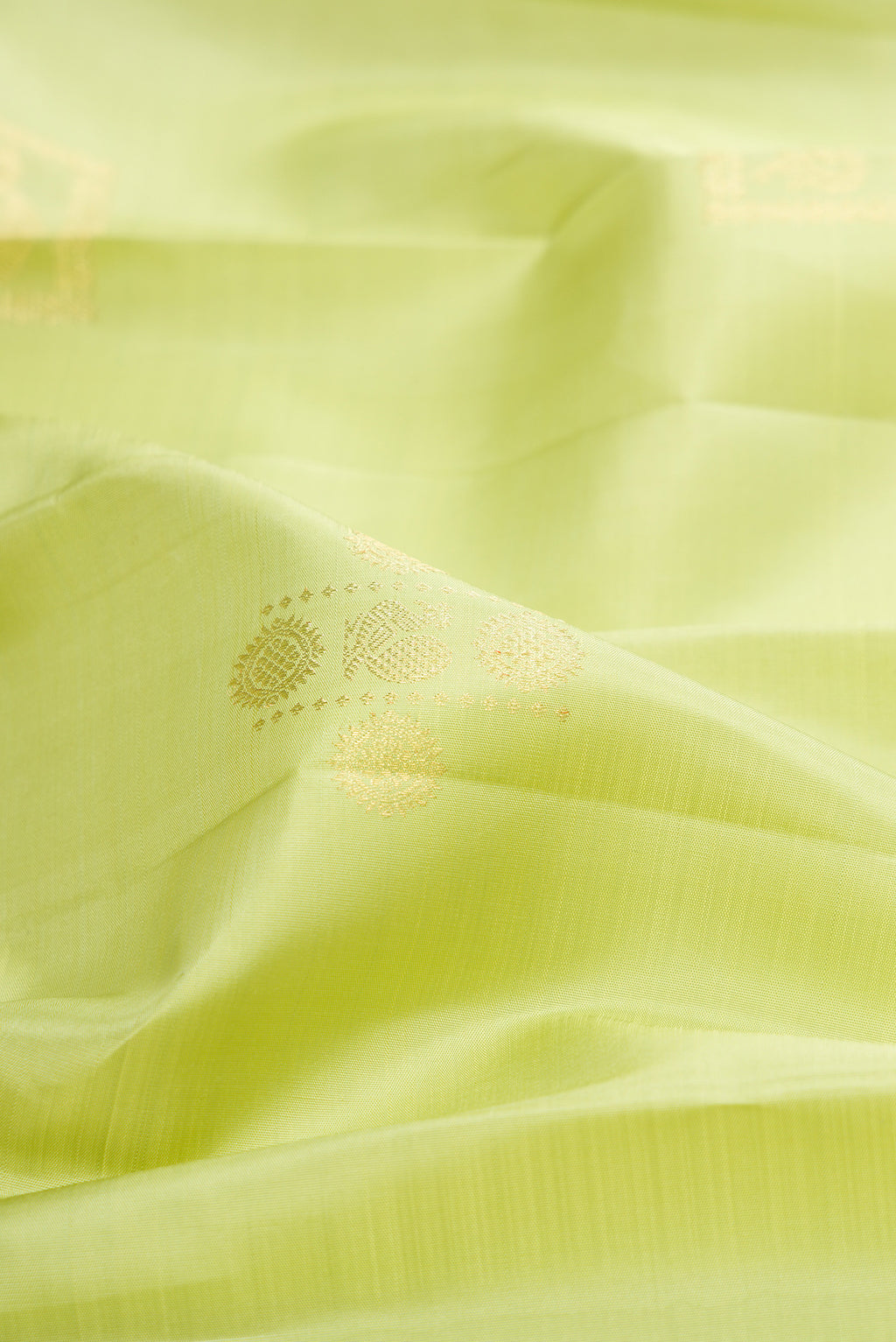 Close up of Pure Silk Pista Green Kanjivaram Saree with Zari Butta on the body and Zari Border.  displaying folds
