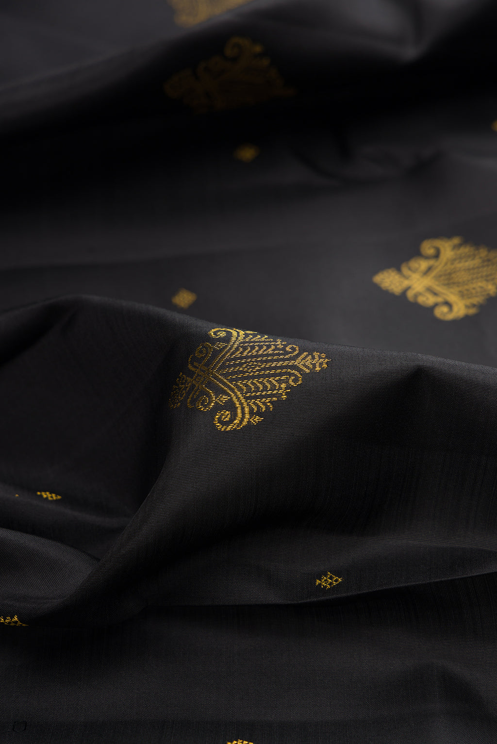 Close up of Pure Silk Black Kanjivaram Saree with Zari Butta on the body and Zari Border.  displaying folds