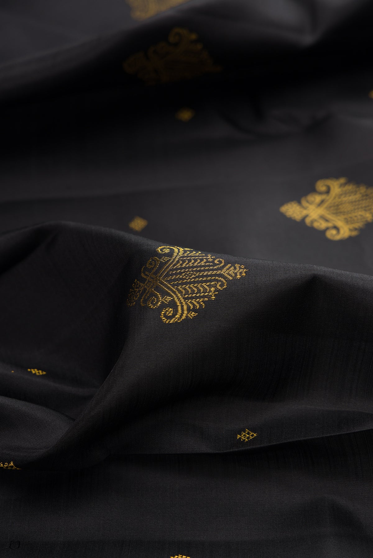 Close up of Pure Silk Black Kanjivaram Saree with Zari Butta on the body and Zari Border.  displaying folds
